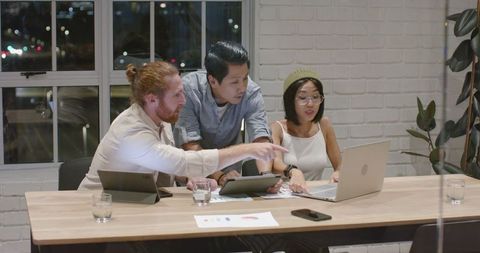Multiracial team discussing project in night office meeting