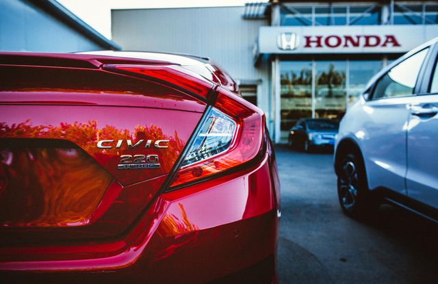 Perfect for illustrating automotive sales concepts, promoting car dealerships, or showcasing new models of Honda vehicles. Highlights dealership setting with focus on red Honda Civic, appealing to potential car buyers and dealerships alike.