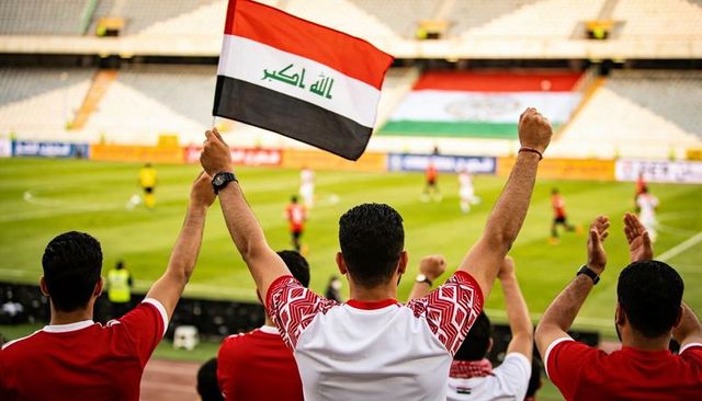 Iraqi football fans cheering and waving national flag in stadium, passionate supporters