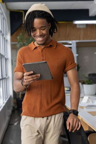 Young african american man smiling using tablet in modern coworking space