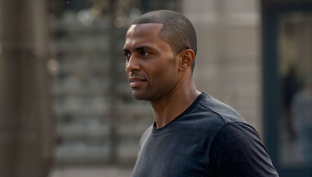 Standing confident african american man gazing left on urban street wearing black t-shirt