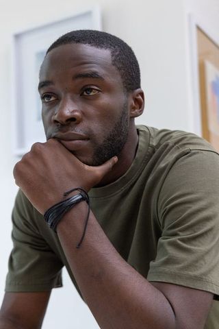 Contemplating african american man resting chin on hand in gallery portrait