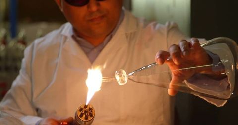 Technician Crafting Glass with Torch in Lab Workshop