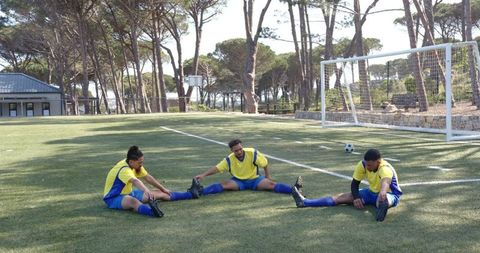 Soccer Players Stretching on Field Under Sunny Sky