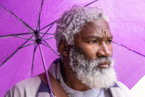 Contemplative senior african american man under purple umbrella closeup portrait