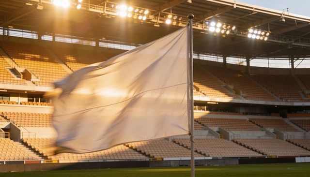 Backlit white corner flag blowing in golden stadium light under floodlights