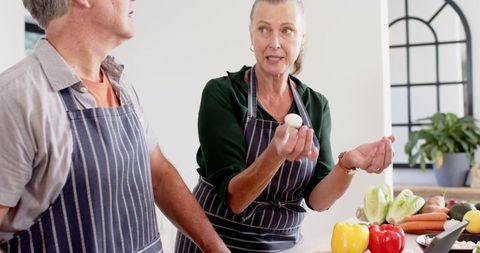 Couple in aprons preparing ingredients in modern kitchen