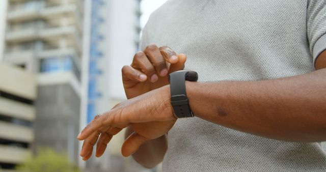 Close-up view of hands interacting with smartwatch in urban setting. Ideal for themes related to technology, wearable devices, modern lifestyle, urban living, and time management.