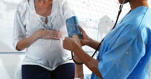 Nurse measuring blood pressure of pregnant patient during prenatal checkup, digital overlay