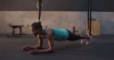 Athletic woman performing plank exercise in gym
