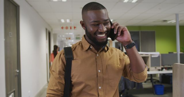 Young professional smiling while having phone conversation in office - Download Free Stock Images Pikwizard.com