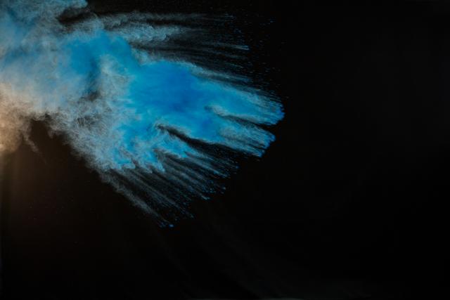 Blue color powder exploding against a black background, creating a dynamic and vibrant splash. Ideal for use in creative projects, advertisements, and artistic designs. Perfect for backgrounds, textures, and abstract art pieces.