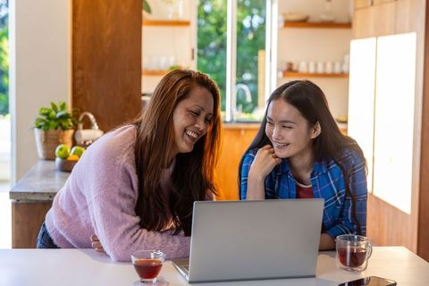 Mother and Daughter Bonding Time at Home Kitchen with Laptop and Tea