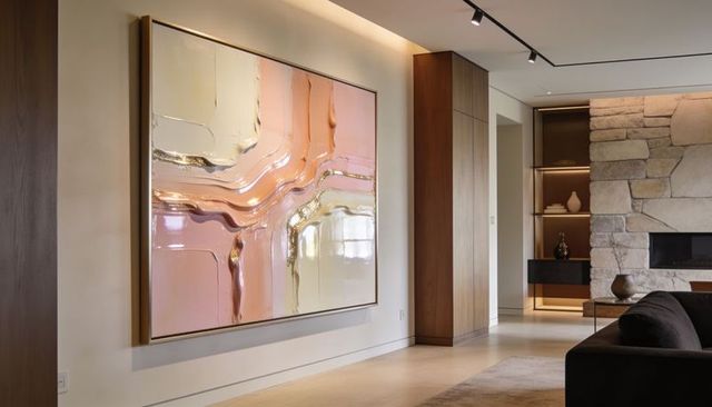 Minimalist living room featuring large abstract pastel painting, gold accents and stone fireplace