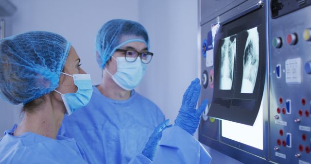 Healthcare professionals in protective gear, standing in an operating room while examining X-ray images. Ideal for medical publications, healthcare marketing, hospital websites, educational materials in medical training, or articles about medical technology and patient care.