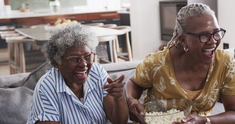 Senior African American Women Watching TV and Enjoying Popcorn