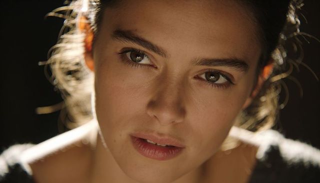 Young woman gazing thoughtfully with warm sidelight and soft rimlight close-up headshot