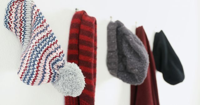 Cozy Winter Hats and Scarves Hanging on Hooks Against White Wall - Download Free Stock Images Pikwizard.com