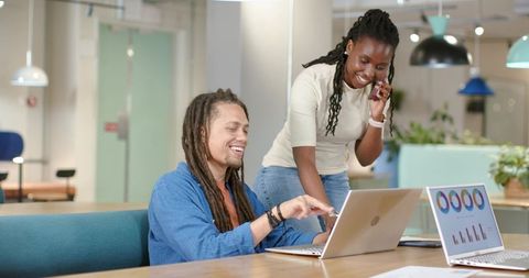 African American coworkers collaborating at coworking table pointing at laptop dashboards