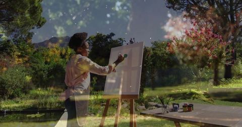 Creative female artist painting in lush garden sanctuary