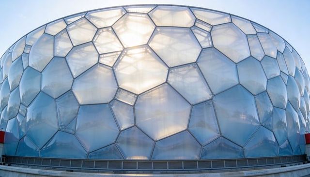 Glowing backlit translucent honeycomb facade featuring curved etfe panels and metal framing