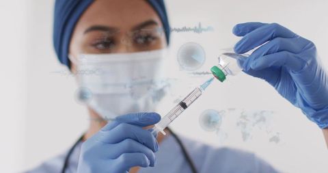 Preparing clinician wearing head covering drawing vaccine into syringe for vaccination