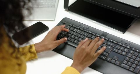 Hands Typing on Keyboard at Office Desk