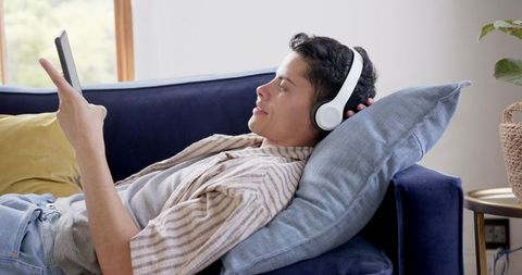 Relaxed Young Man Using Smartphone with Headphones on Couch