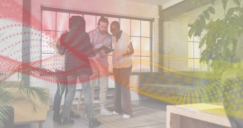 Collaborating around tablet in modern loft workspace with greenery, large windows, coworking