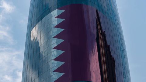 Curved glass tower reflecting skyline with maroon serrated facade for modern urban design