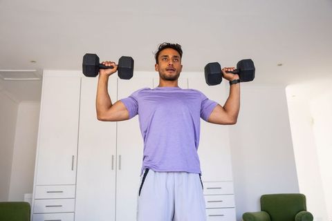 Asian man lifting weights in modern home gym with minimalist design