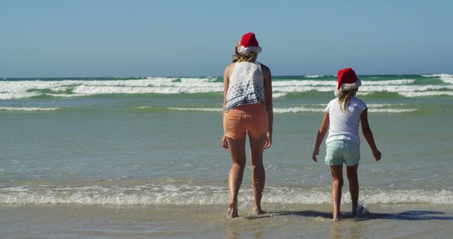 Mother and Daughter Enjoying Christmas Day at the Beach Wearing Santa Hats - Download Free Stock Images Pikwizard.com