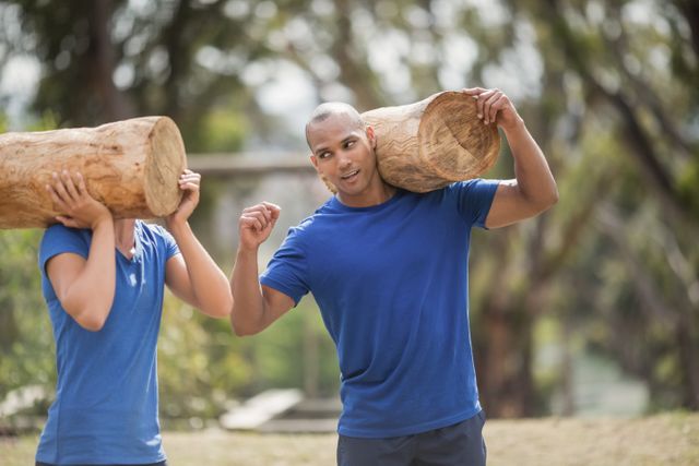 People participating in a boot camp, carrying heavy wooden logs as part of an obstacle course. Ideal for illustrating teamwork, physical fitness, outdoor training, and endurance challenges. Suitable for fitness blogs, training programs, and motivational content.