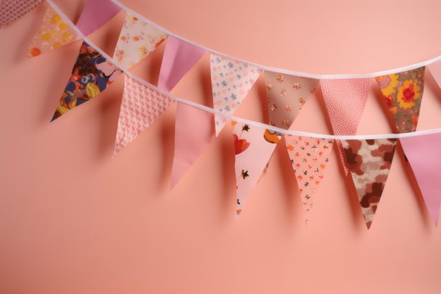 Colorful triangle bunting flags on pink background. Ideal for decorating birthday parties, baby showers, wedding receptions, or festive events. Perfect for adding a cheerful and vibrant touch to indoor party settings.