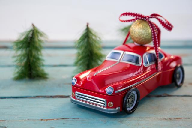 Toy car carrying christmas bauble ball on wooden plank during christmas time