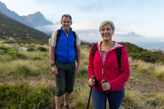 Portrait of caucasian hiker senior couple with backpack and hiking poles trekking in the mountains. trekking hiking and adventure concept.