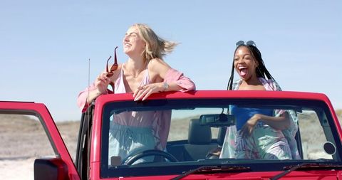 Carefree Friends on Joyful Beach Road Trip in Red Vehicle