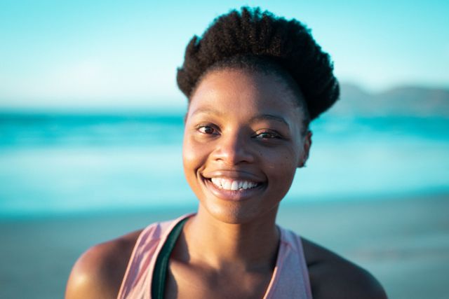 Portrait of african american woman looking at camera and smiling. holiday, freedom and leisure time at the beach. or lesbians