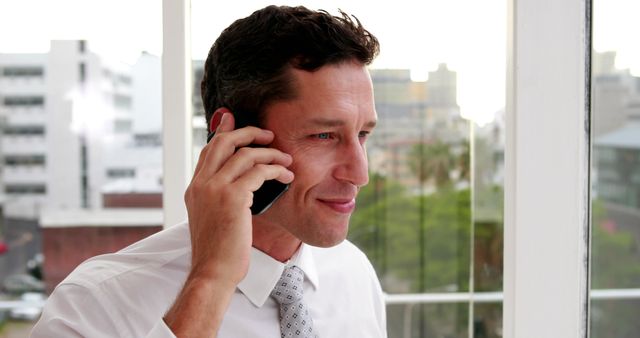 Businessman smiling while talking on cellphone in modern office - Download Free Stock Images Pikwizard.com