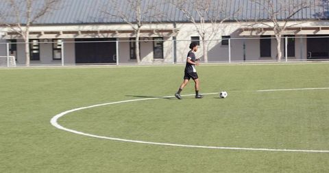 Lone male soccer player dribbling on sunny field