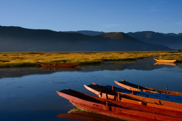 Colorful Canoes on Tranquil Lake at Dawn with Mountain Views - Download Free Stock Photos Pikwizard.com