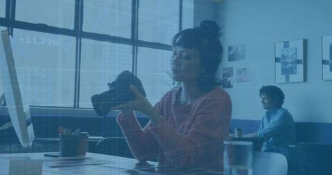 Woman adjusting dslr lens in modern office with tech overlays