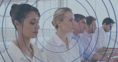 Focused professional team sitting in row using laptops with blue concentric ring overlay