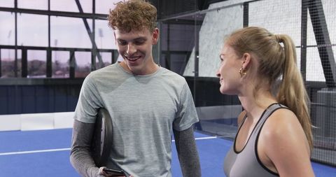 Sports Partners Enjoying Padel Court with Smartphone and Racket