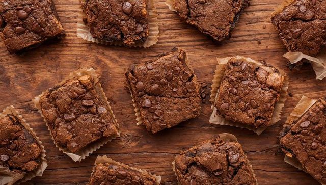 Fudgy Chocolate Brownie Squares on Rustic Wood with Parchment Liners and Chocolate Chips