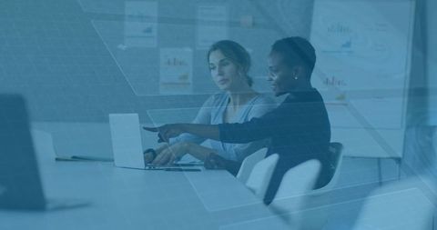Businesswomen Collaborating on Laptop in Modern Office