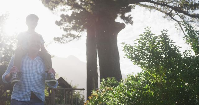 A veteran holding a child on his shoulders, enjoying a sunny day outdoors. The background includes tall trees and lush greenery. Perfect for use in campaigns promoting family time, nature outings, or veteran recognition. Can also be used for advertisements related to family services, outdoor activities, or community events.