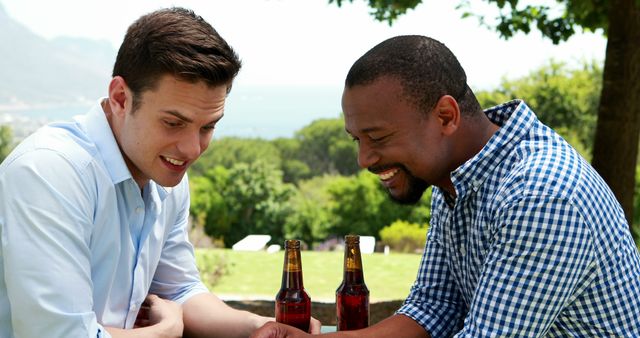 Two friends are sharing a moment by drinking and chatting outdoors on a sunny day. Ideal for use in campaigns promoting friendly gatherings, leisure activities, diversity, or outdoor lifestyles. Great for illustrating social interactions, relaxation, and enjoyable times with friends.