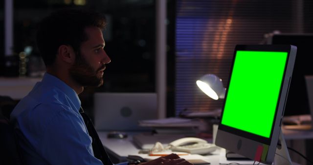 Man Working Late-Night in Office with Blank Green Screen Monitor - Download Free Stock Images Pikwizard.com