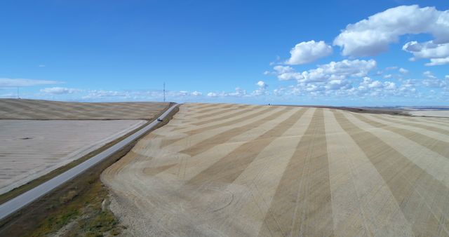 Vast agricultural fields stretch under a blue sky. Patterns in the landscape indicate modern farming techniques and the scale of agriculture.